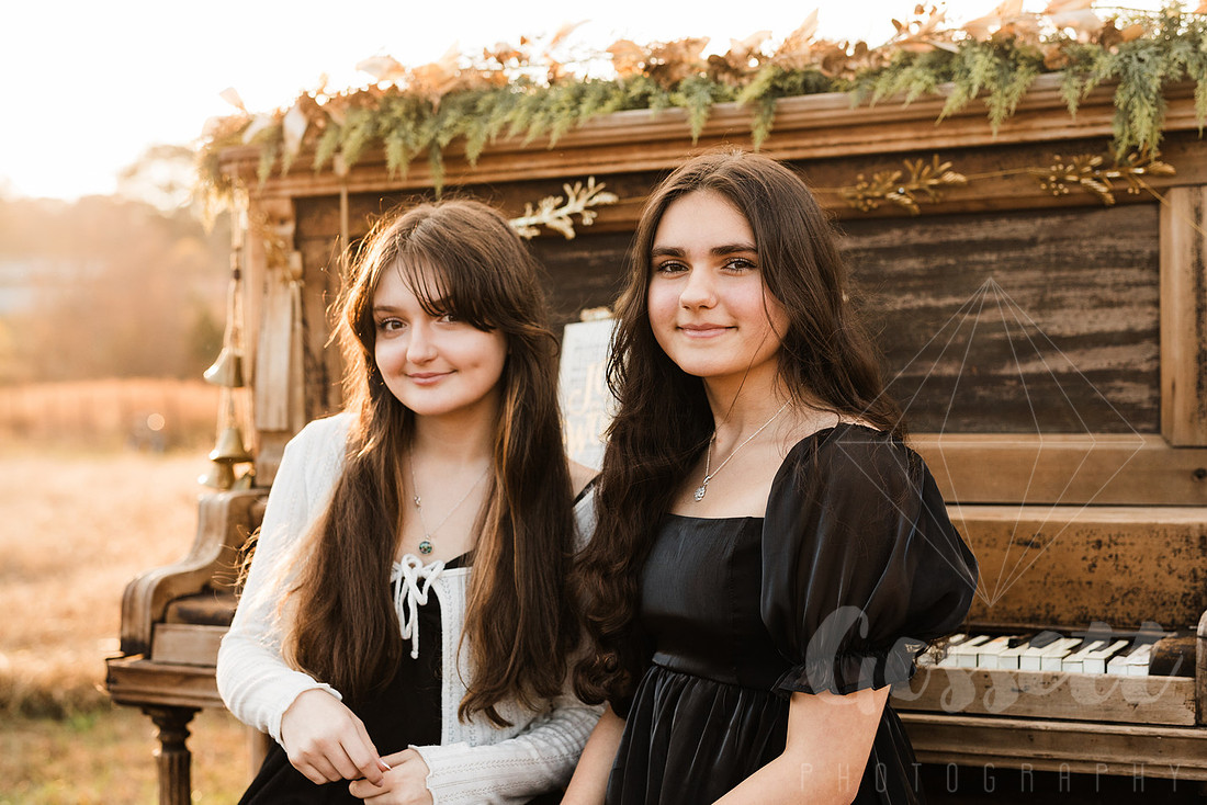 a family gathers around a vintage piano in a golden field for a christmas mini session