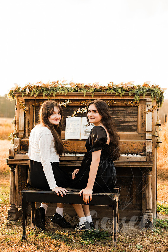 a family gathers around a vintage piano in a golden field for a christmas mini session