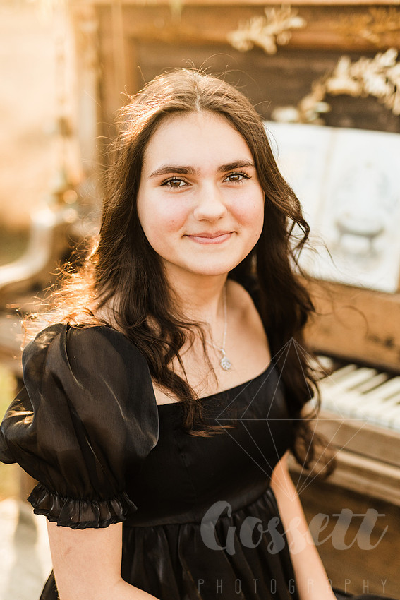 a family gathers around a vintage piano in a golden field for a christmas mini session