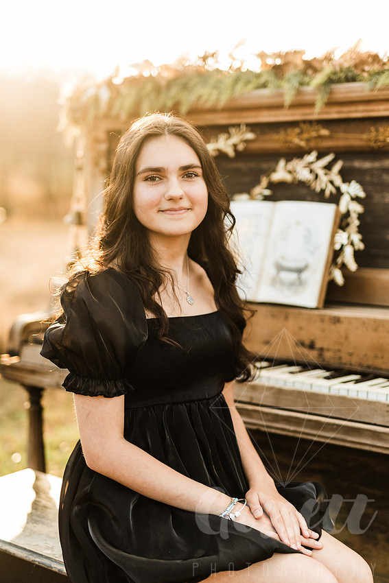 a family gathers around a vintage piano in a golden field for a christmas mini session