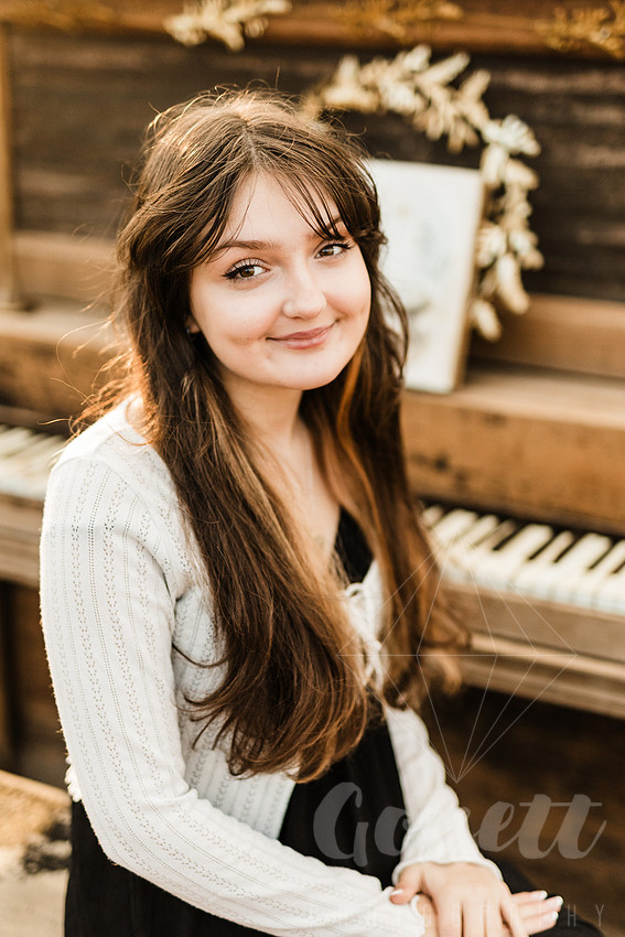a family gathers around a vintage piano in a golden field for a christmas mini session