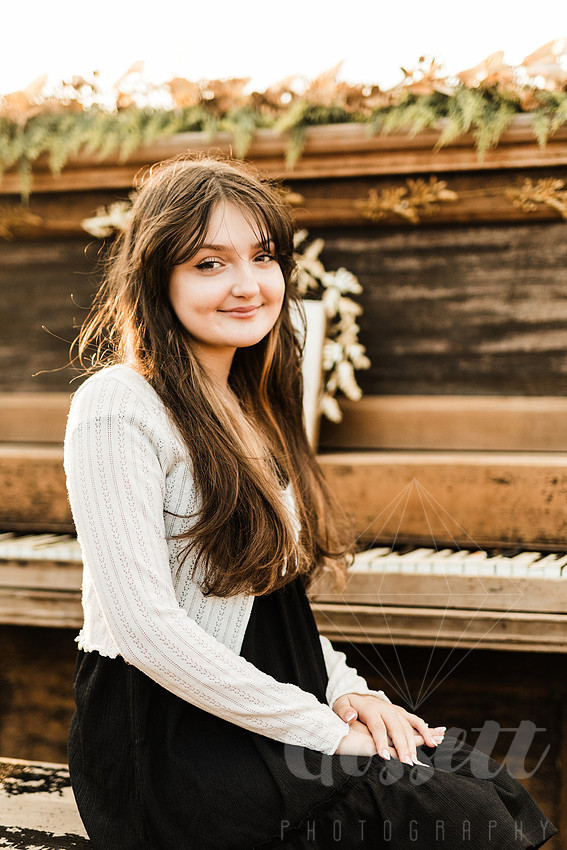 a family gathers around a vintage piano in a golden field for a christmas mini session