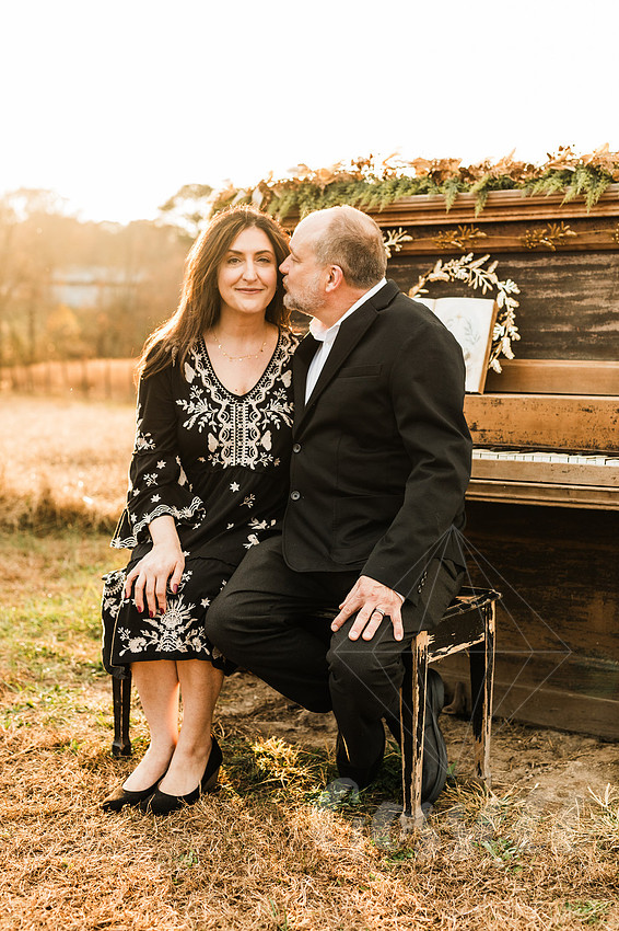 a family gathers around a vintage piano in a golden field for a christmas mini session