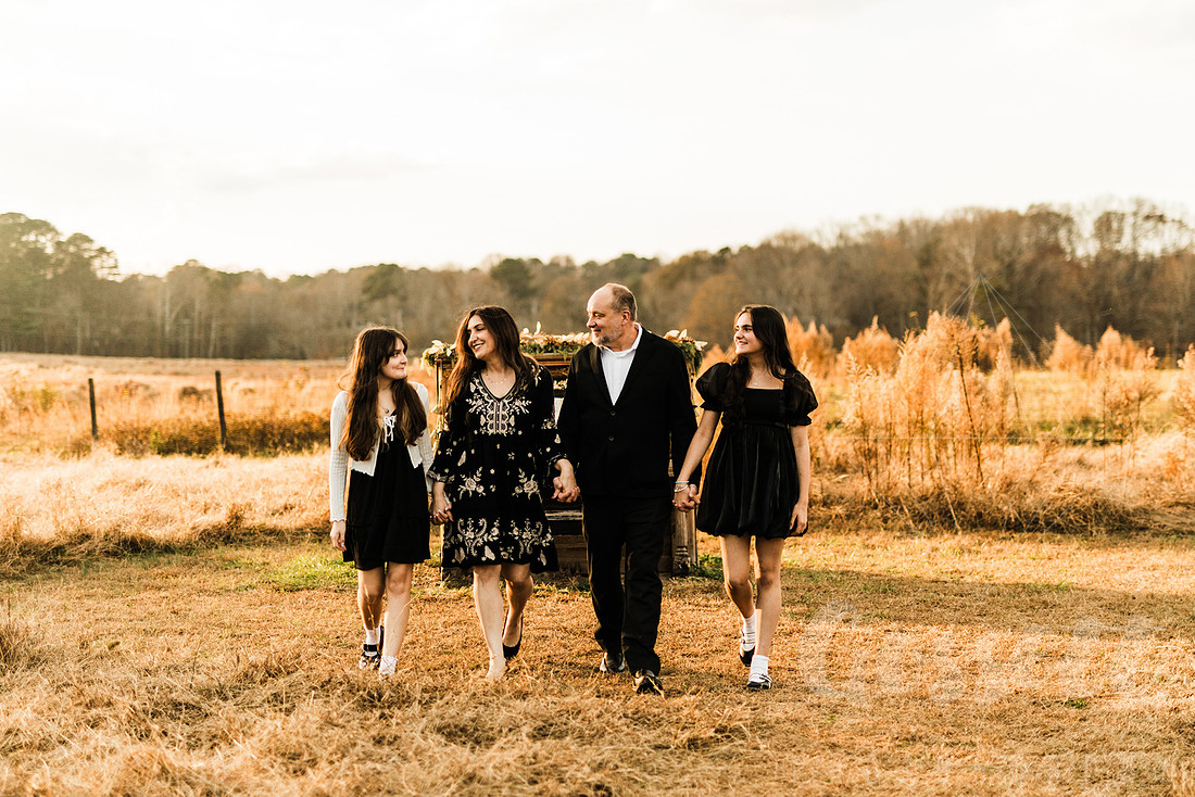 a family gathers around a vintage piano in a golden field for a christmas mini session