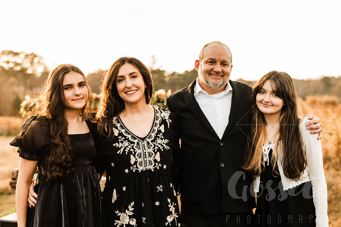 a family gathers around a vintage piano in a golden field for a christmas mini session