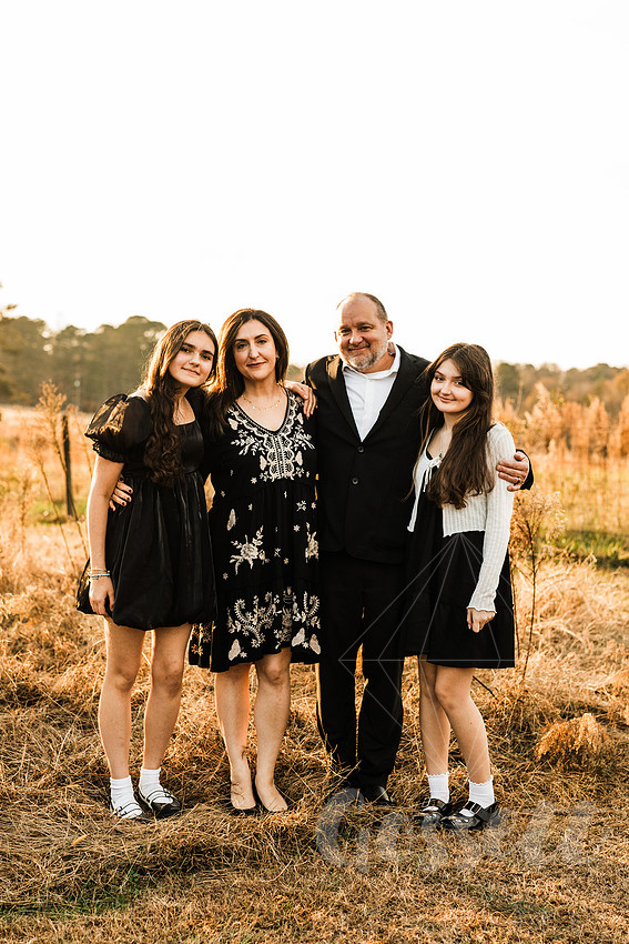 a family gathers around a vintage piano in a golden field for a christmas mini session