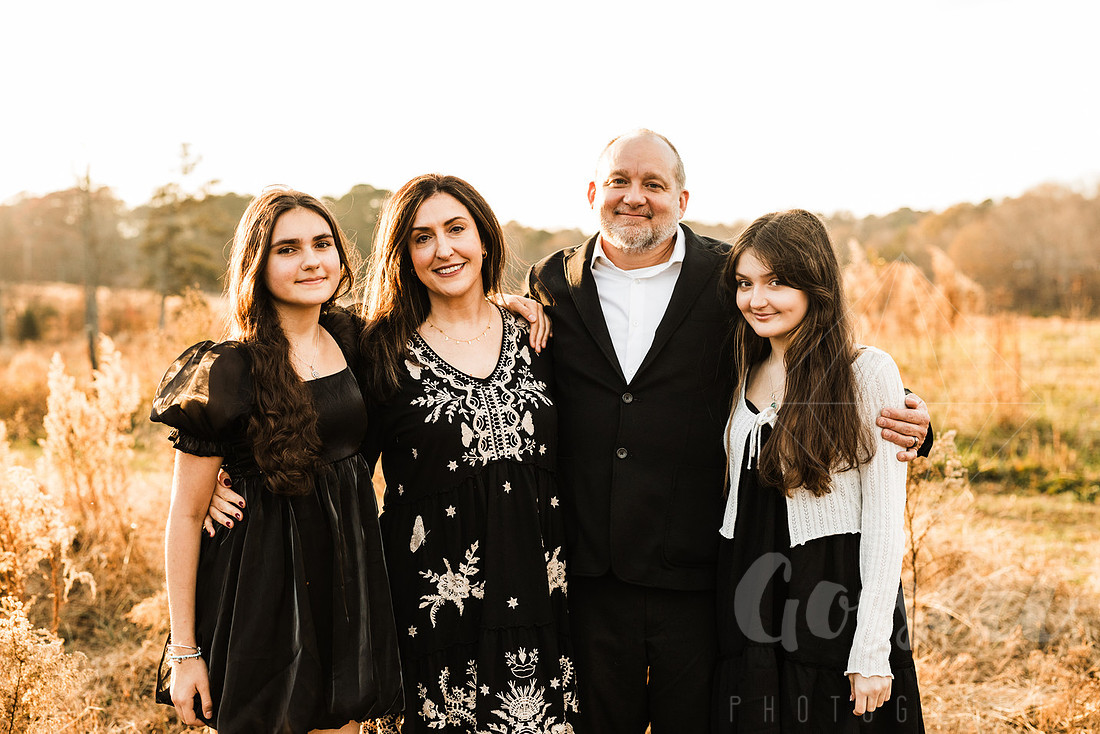 a family gathers around a vintage piano in a golden field for a christmas mini session