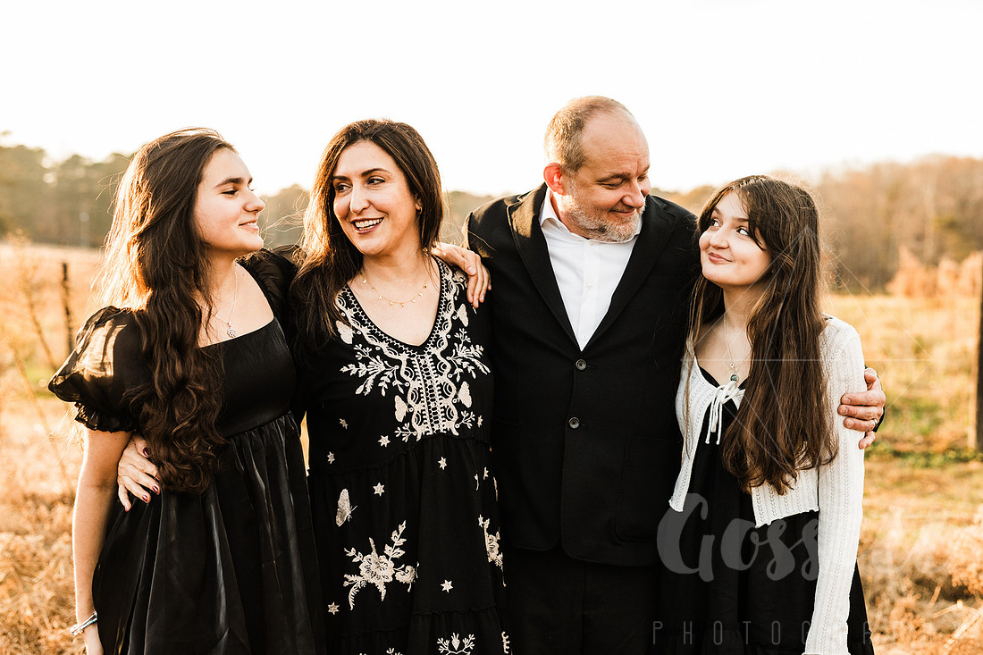 a family gathers around a vintage piano in a golden field for a christmas mini session