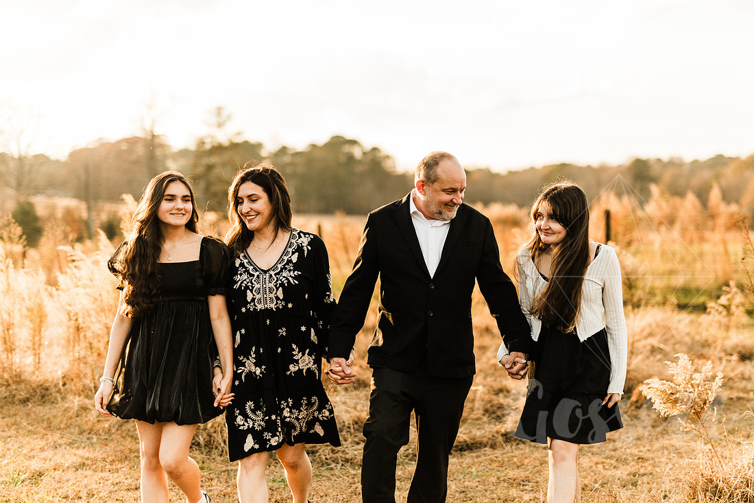 a family gathers around a vintage piano in a golden field for a christmas mini session