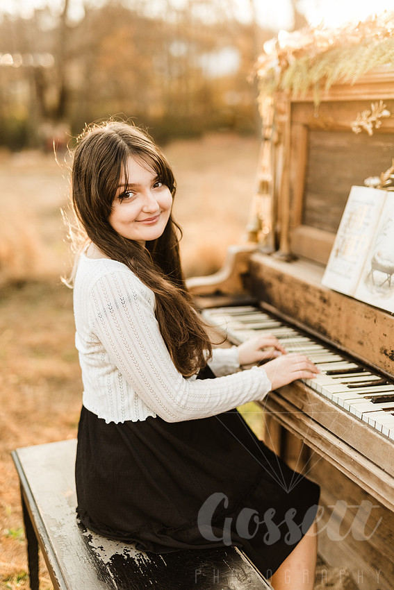 a family gathers around a vintage piano in a golden field for a christmas mini session