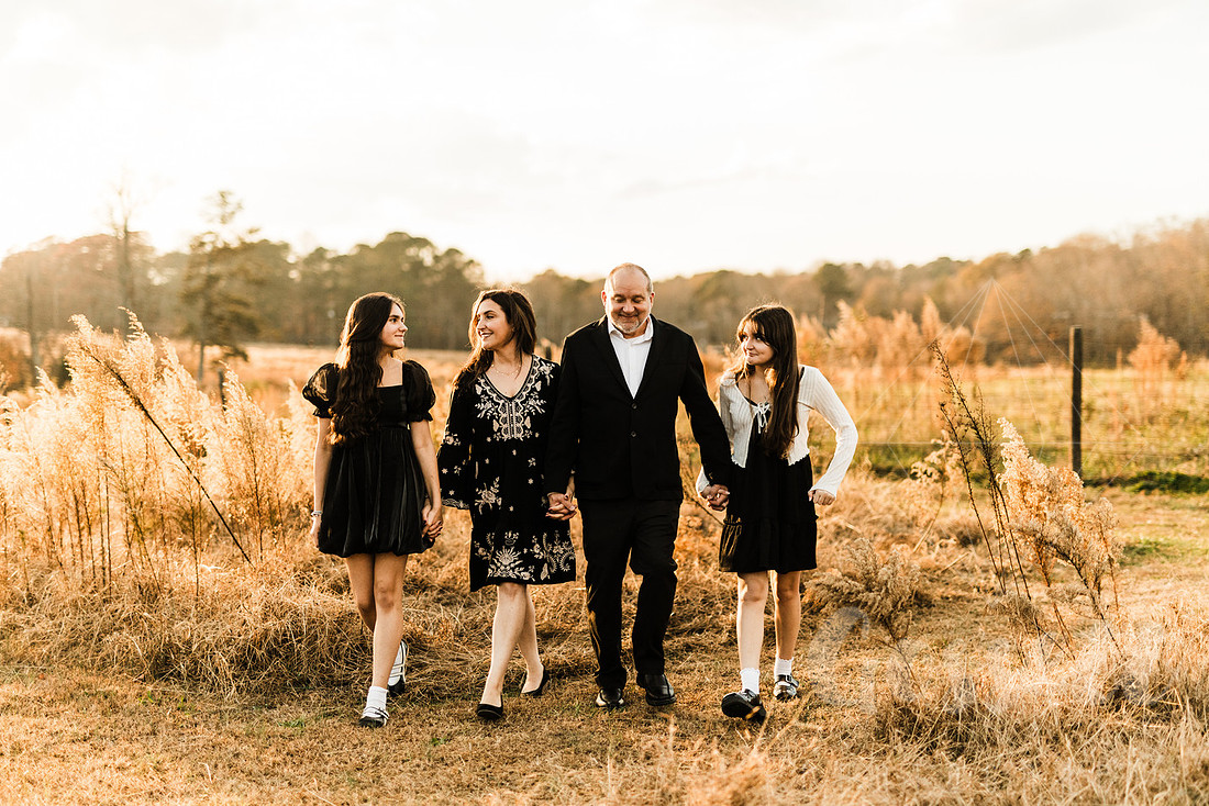 a family gathers around a vintage piano in a golden field for a christmas mini session