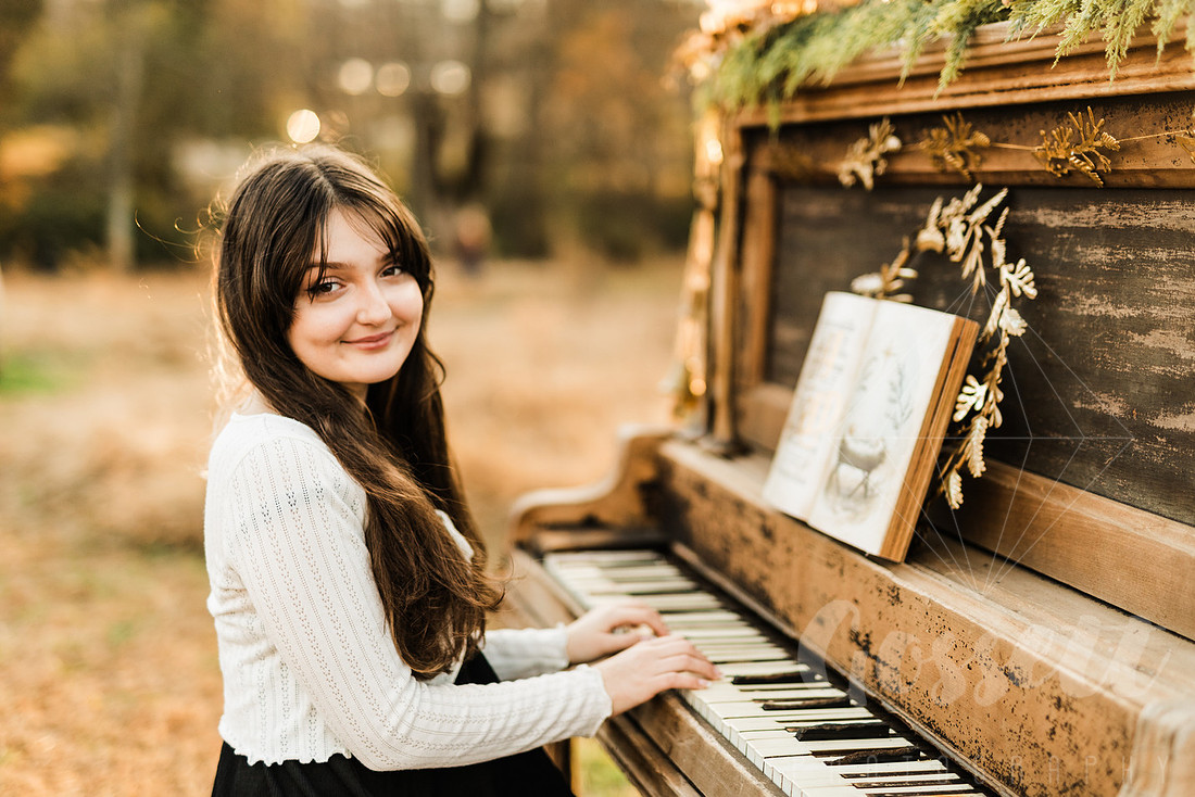 a family gathers around a vintage piano in a golden field for a christmas mini session