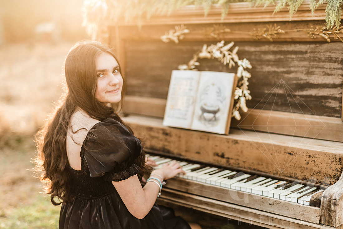 a family gathers around a vintage piano in a golden field for a christmas mini session