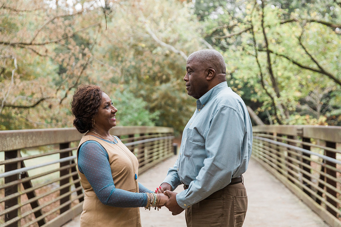 Parents and grown adult children smiling together outdoors during a family portrait session.