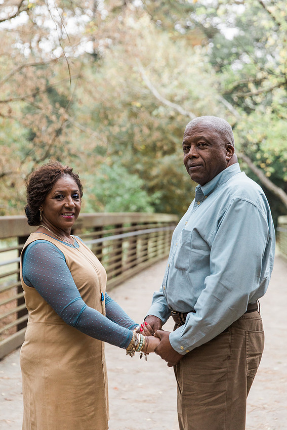 Parents and grown adult children smiling together outdoors during a family portrait session.