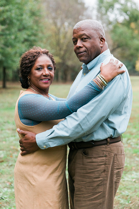 Parents and grown adult children smiling together outdoors during a family portrait session.