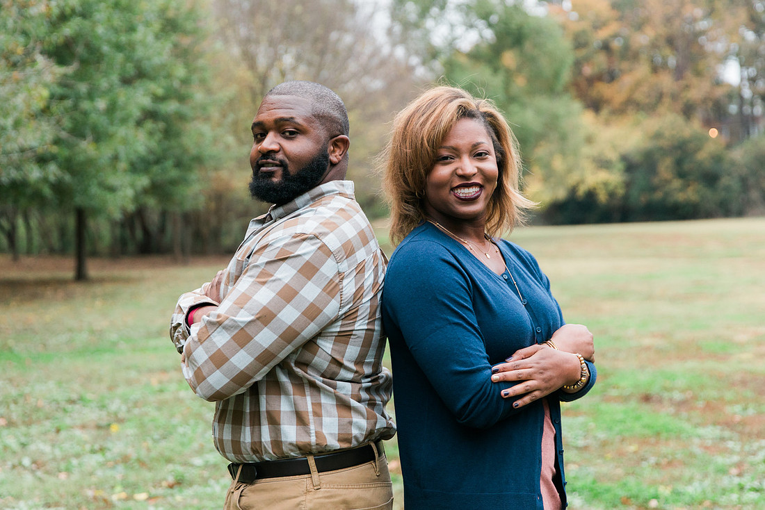 Parents and grown adult children smiling together outdoors during a family portrait session.