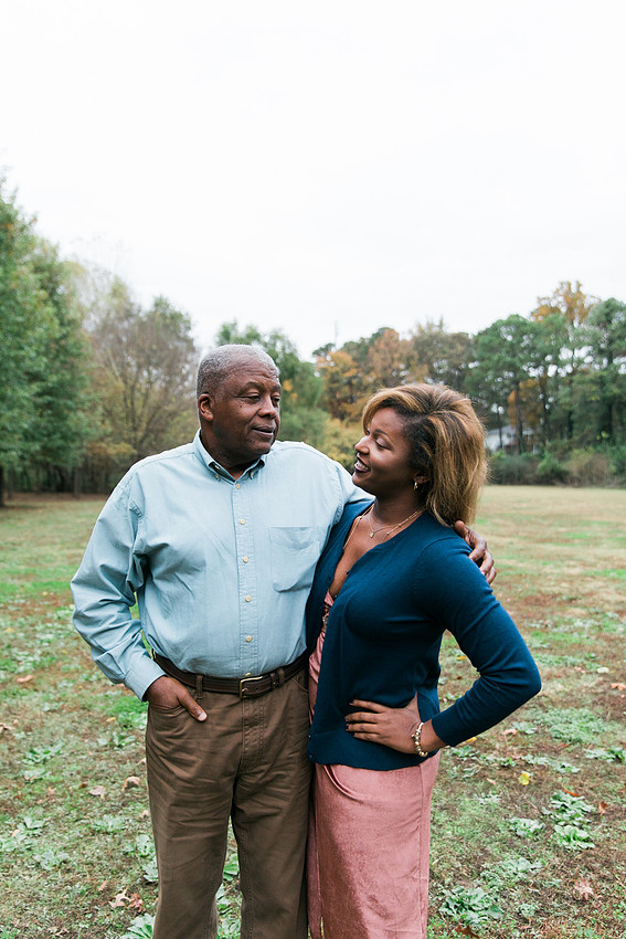 Parents and grown adult children smiling together outdoors during a family portrait session.