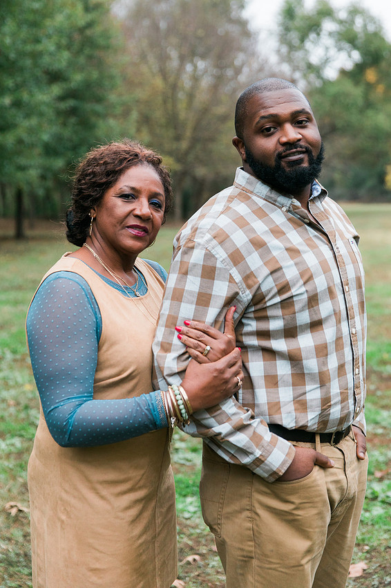 Parents and grown adult children smiling together outdoors during a family portrait session.