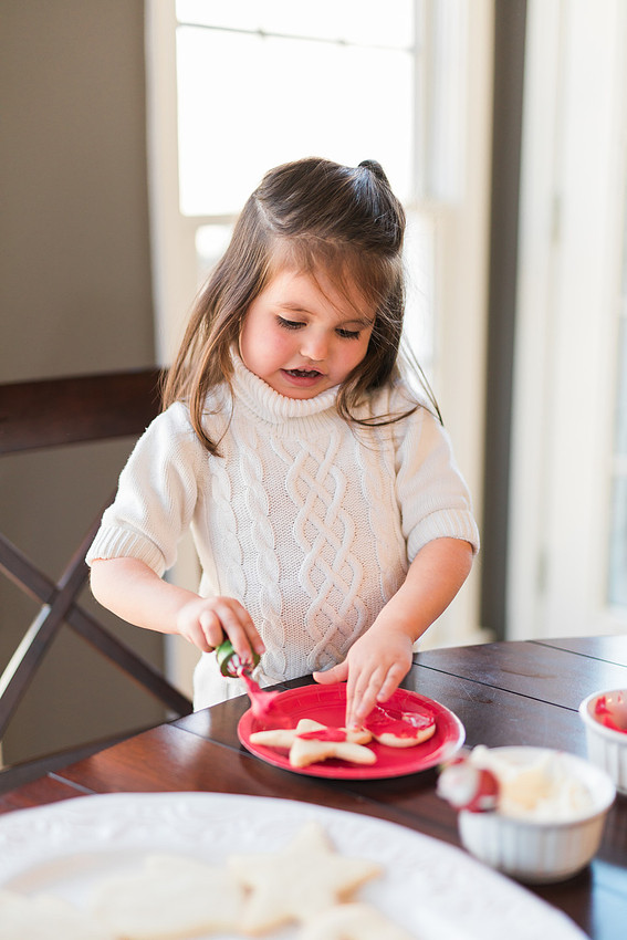 family bakes holiday cookies in their home while photographer captures candid moments