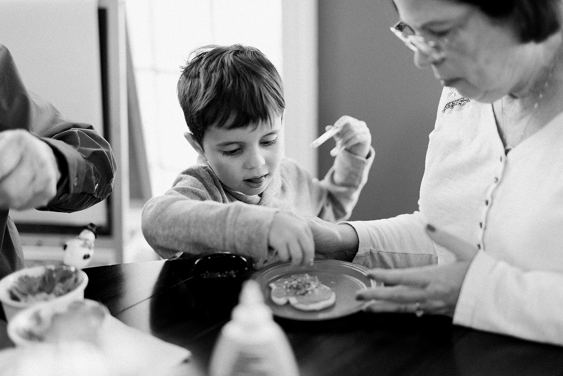 family bakes holiday cookies in their home while photographer captures candid moments