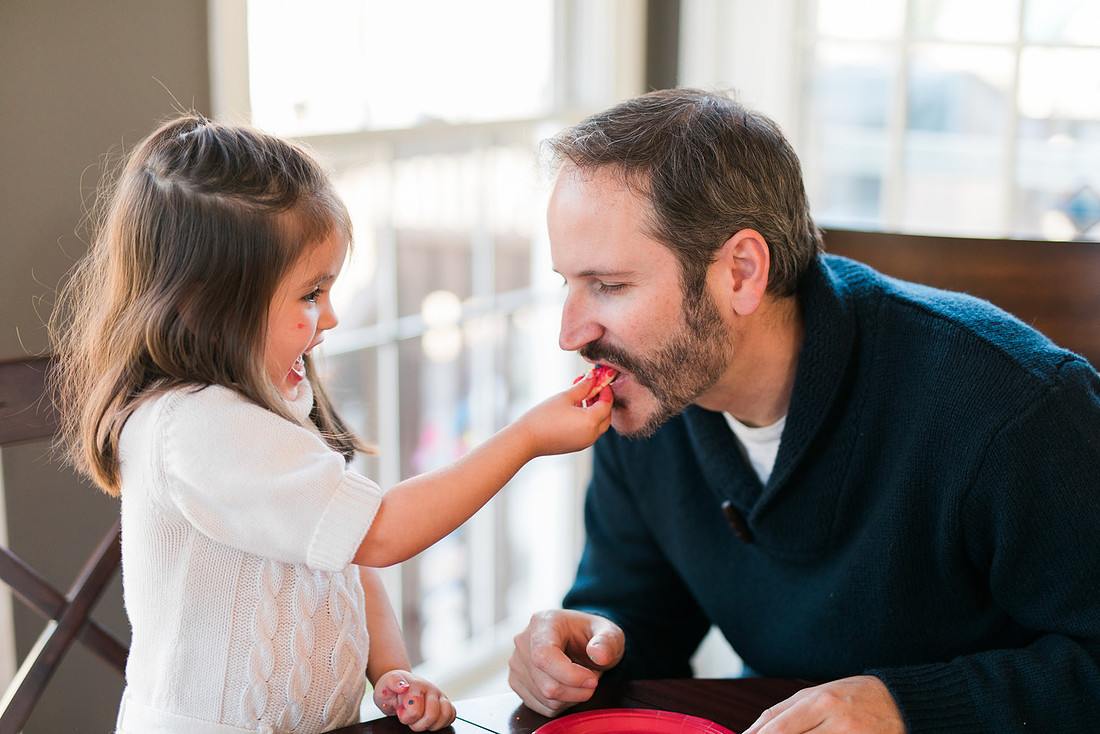 family bakes holiday cookies in their home while photographer captures candid moments