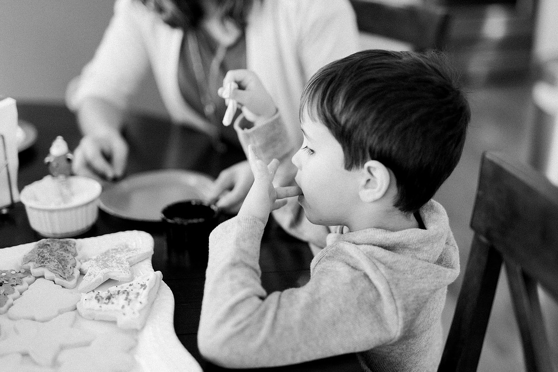 family bakes holiday cookies in their home while photographer captures candid moments