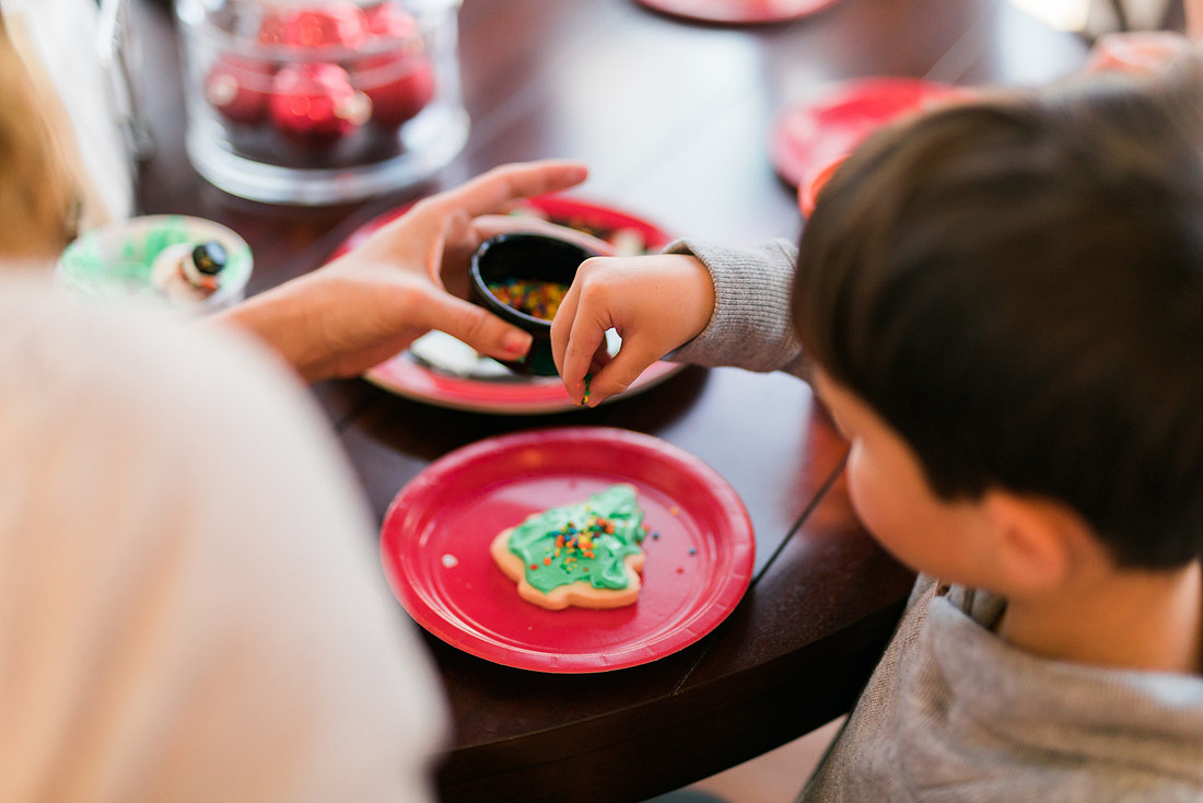 family bakes holiday cookies in their home while photographer captures candid moments