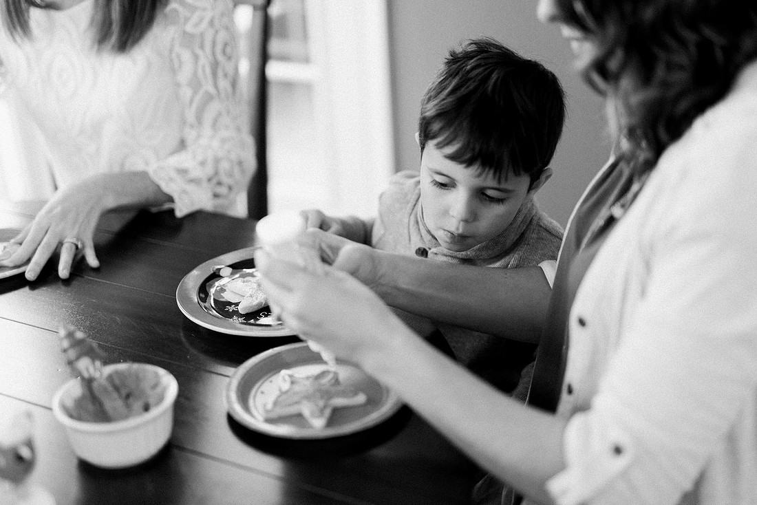 family bakes holiday cookies in their home while photographer captures candid moments