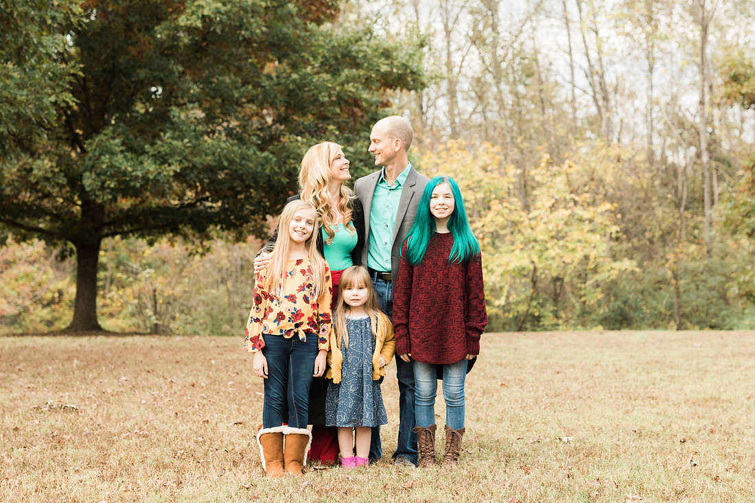 Family smiles for both posed and candid photos in a park