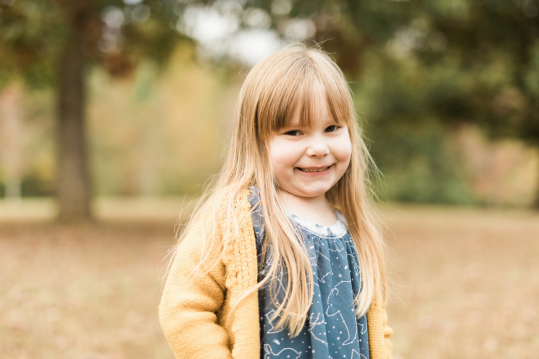 Family smiles for both posed and candid photos in a park