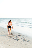 High school senior girl writing her graduation year in the sand during a photo shoot.