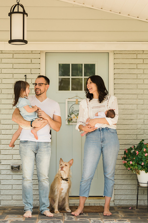 Family laughs together candidly on their front porch.