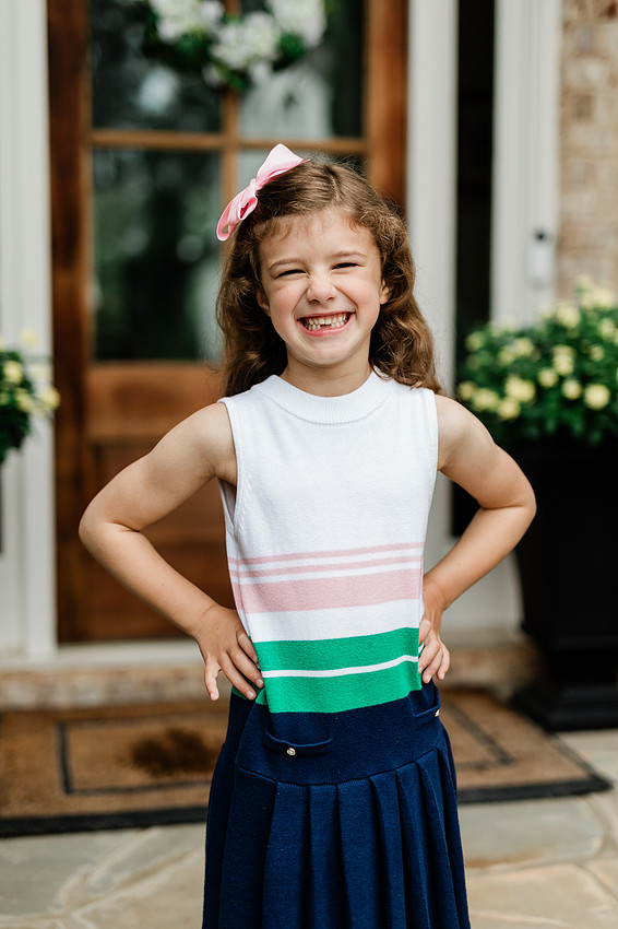 girl smiles for the camera on her front porch the day before starting kindergarten in cobb county