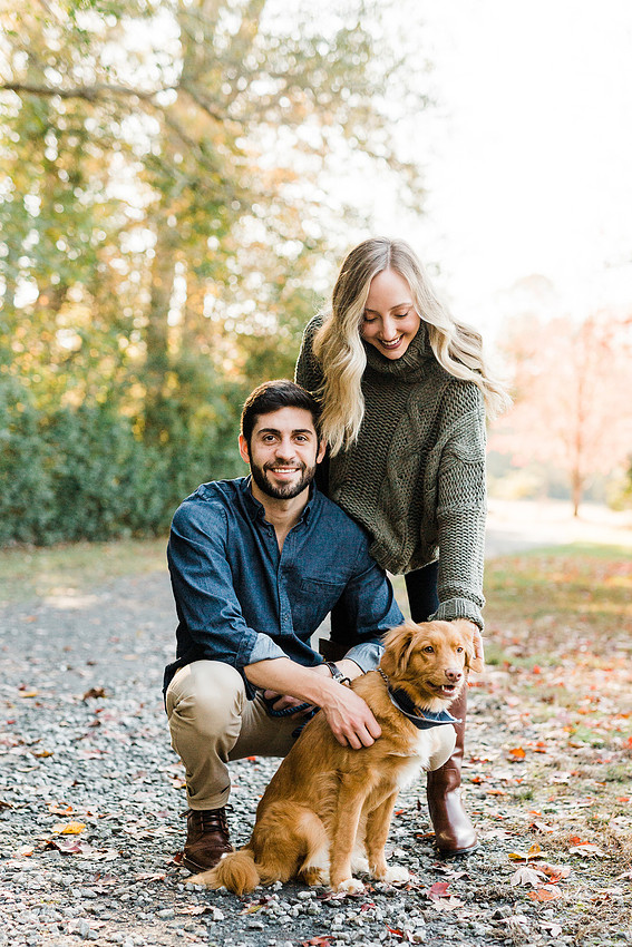 couple smiles with their dog, at a park