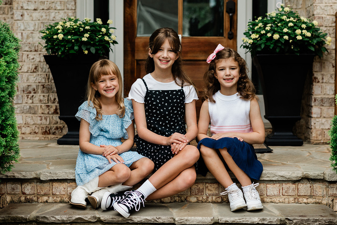 sisters together on their front porch, smiling for the first day of school.