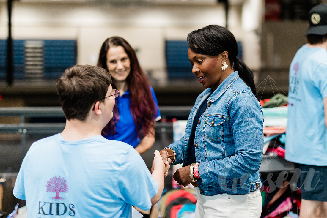 Cobb County Chairwoman Lisa Cupid shakes the hand of a young volunteer at the school supply drive. 
