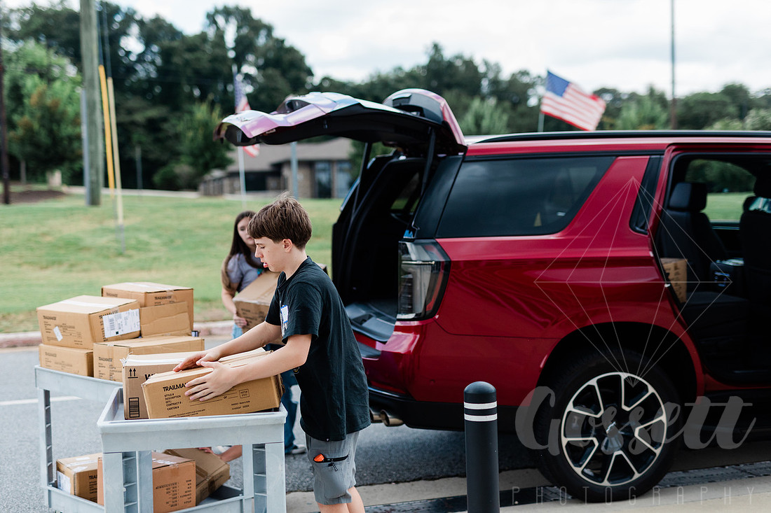 Boy loads cart of school supplies, just donated, outside of Cobb County Civic, where they will be sorted. 