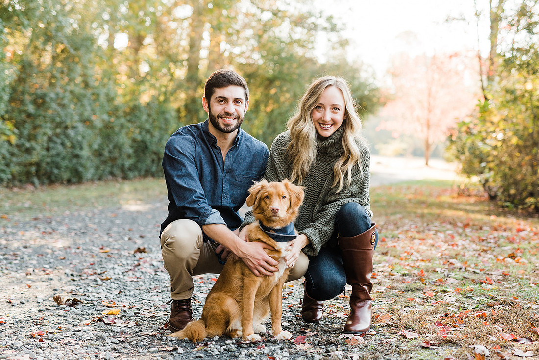 couple smiles with their dog, at a park