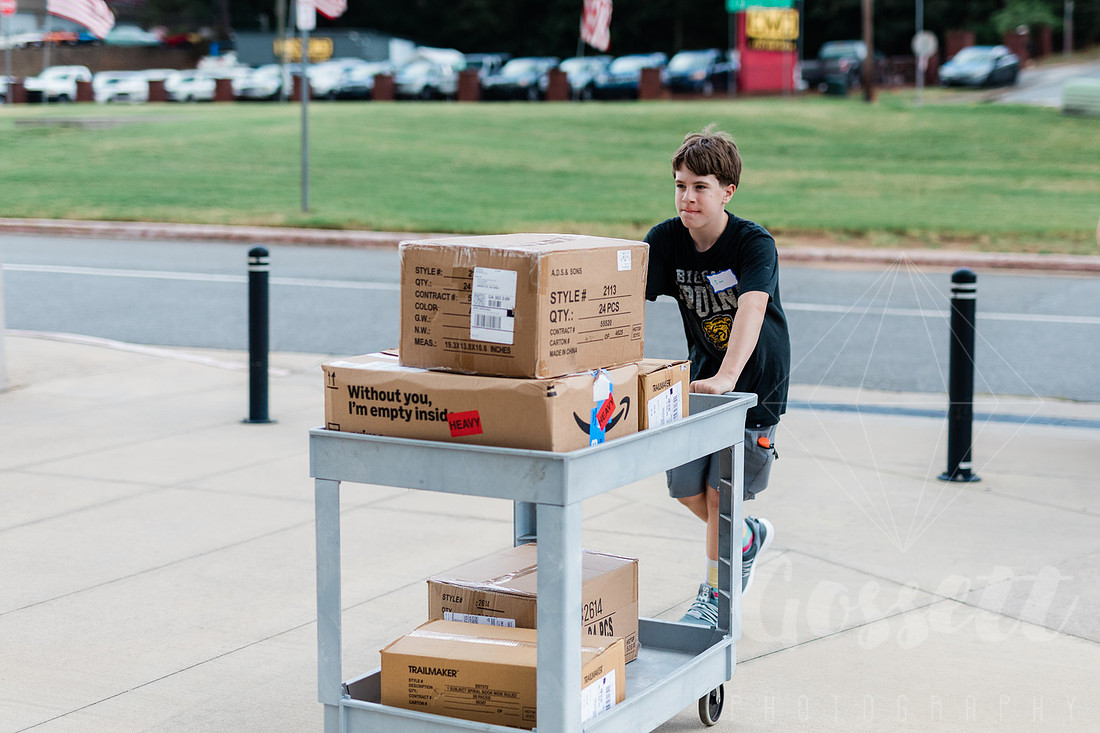 Boy pushes cart full of donated school supplies into the Cobb Civic Center so they can be sorted. 