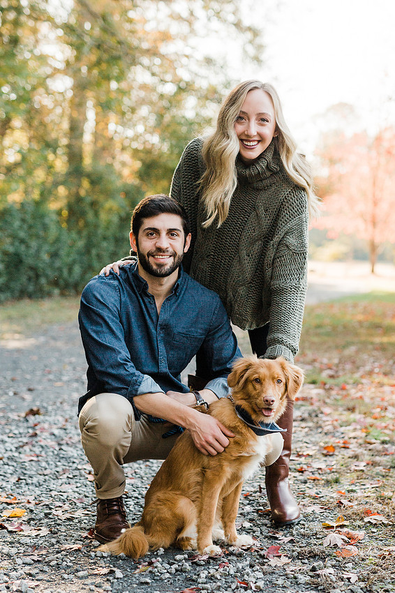 couple smiles with their dog, at a park